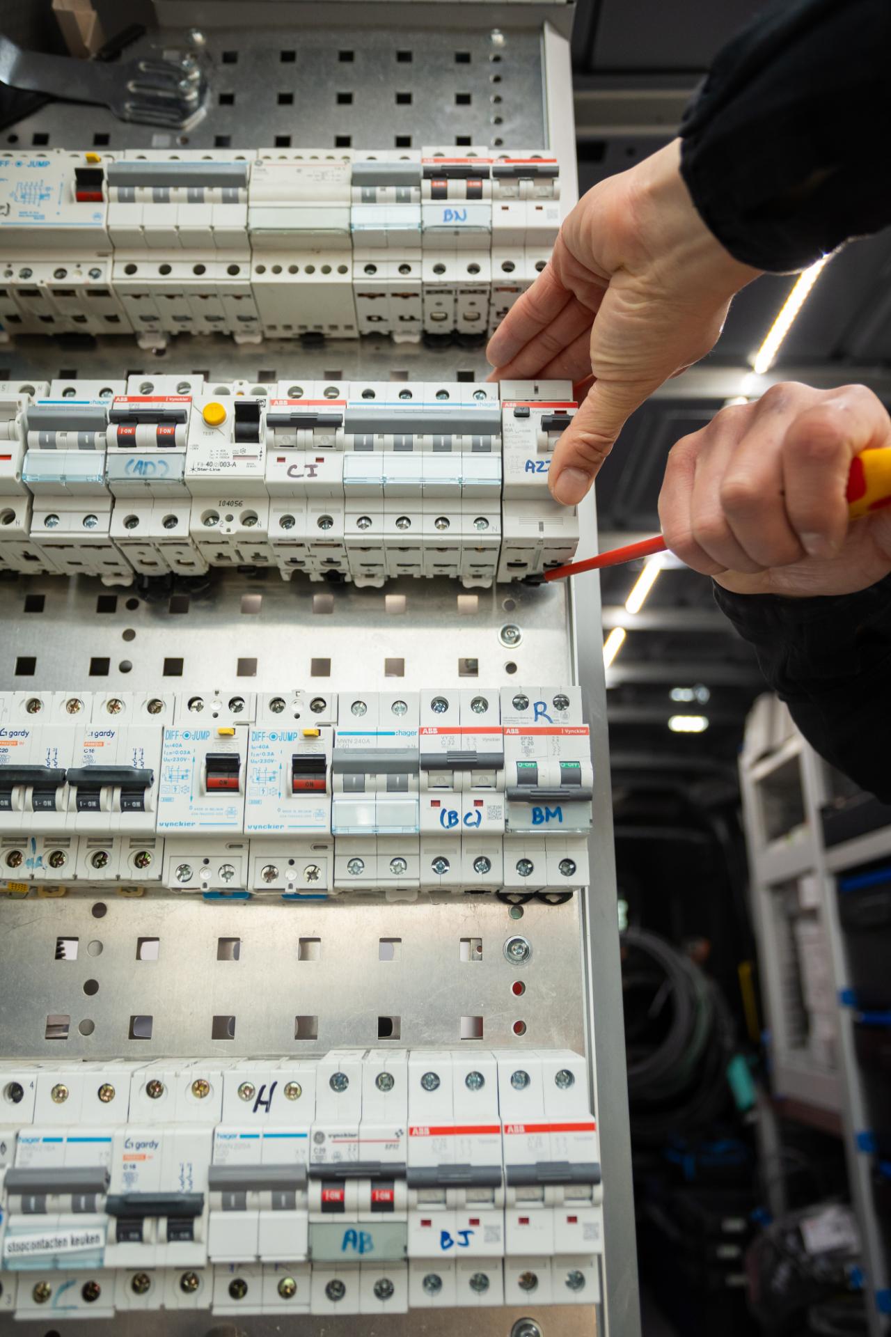 Elektricien plaatst componenten in zekeringkast met schroevendraaier